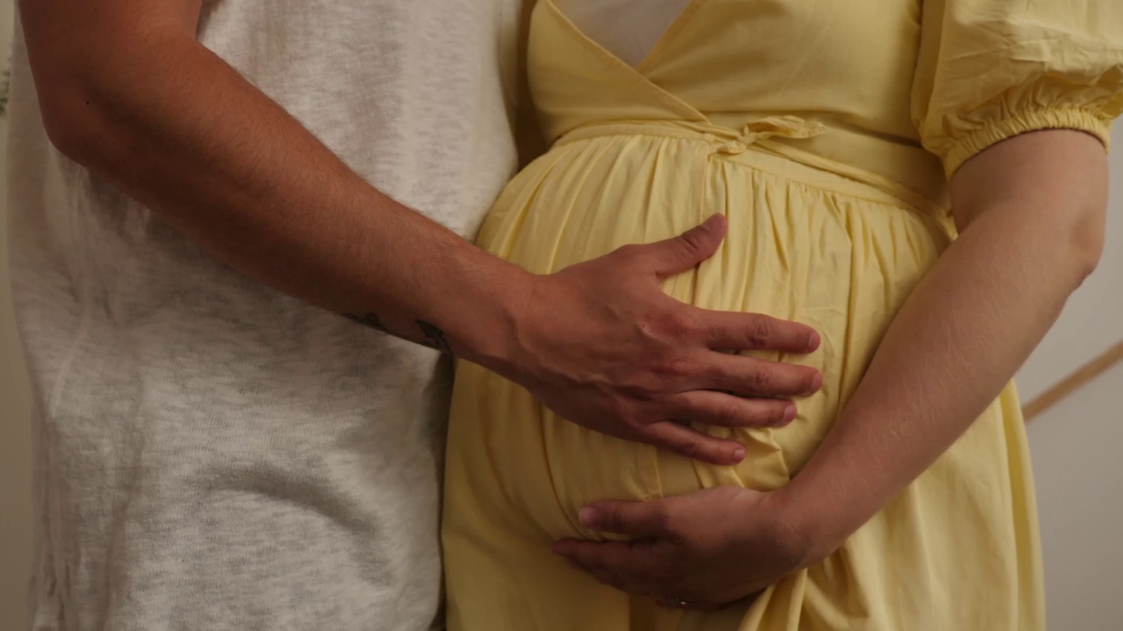 Expectant parents resting their hands together